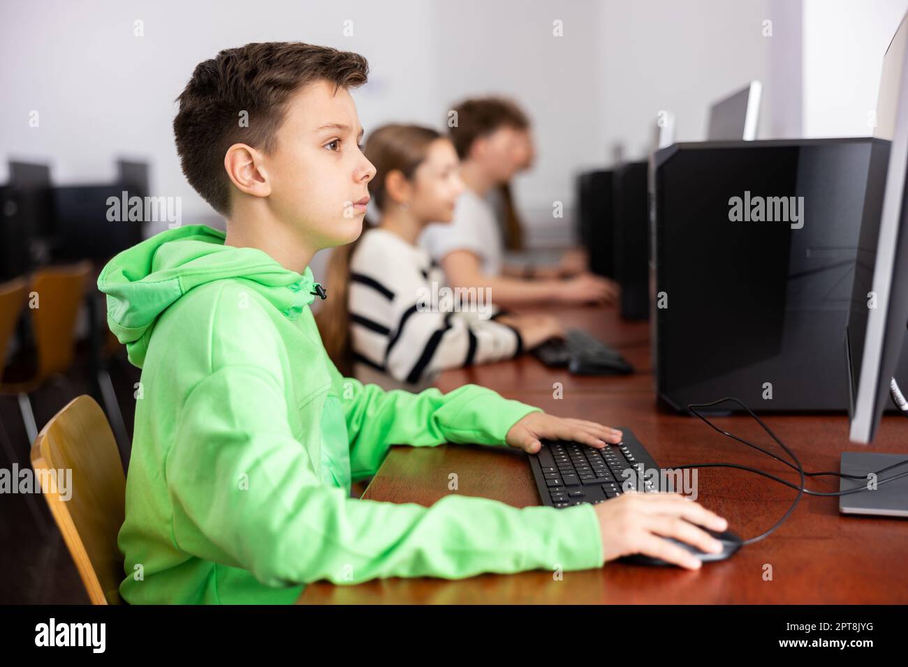 Ha messo a fuoco il ragazzo di Tween che studia con i compagni di classe in laboratorio del calcolatore Foto Stock