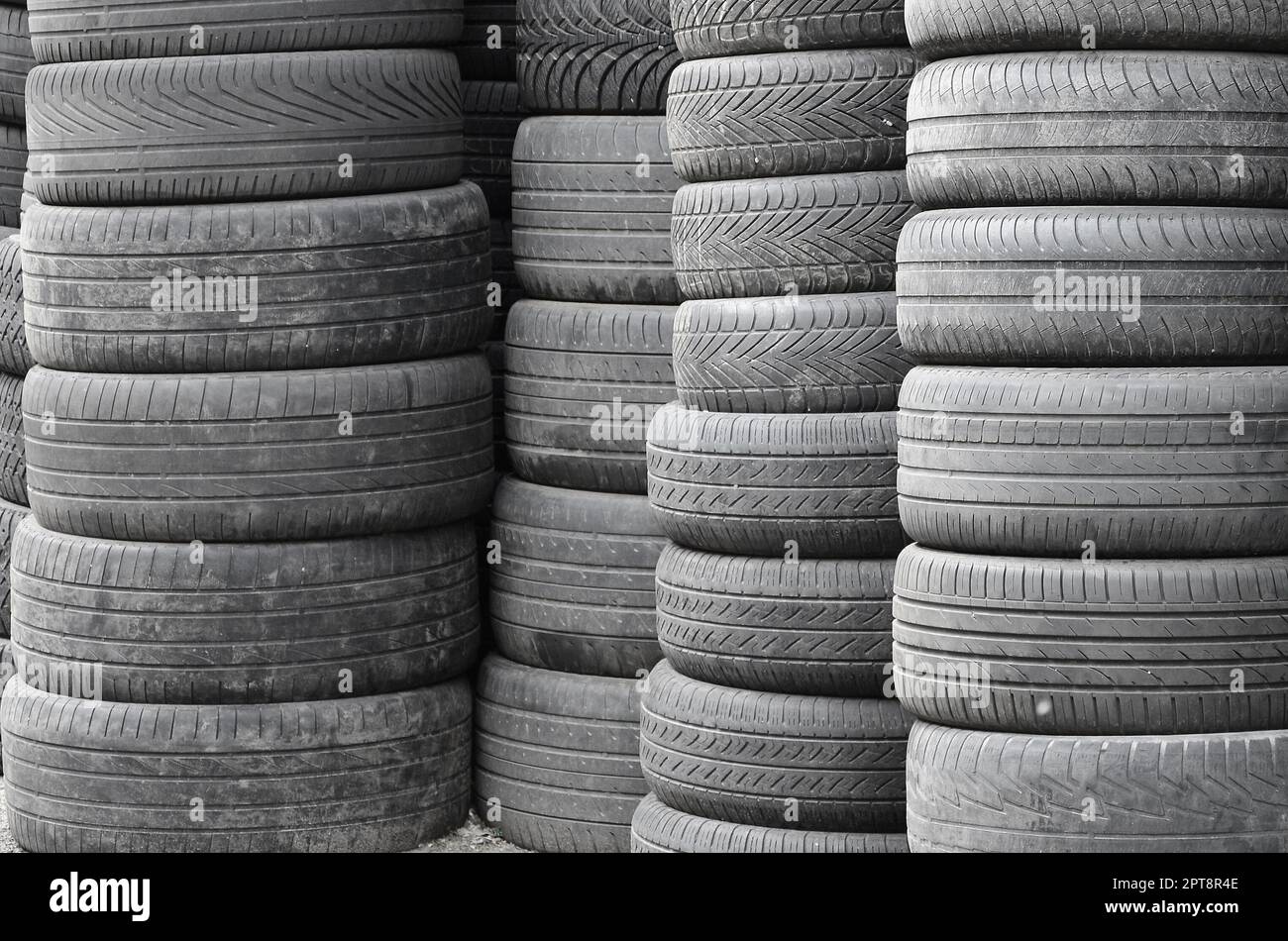 Vecchi pneumatici usati impilati con pali alti nel secondario di parti per auto shop garage vicino fino Foto Stock