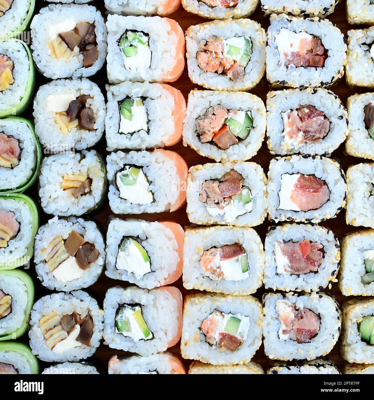 Primo piano di un sacco di sushi roll con diversi ripieni. Macrofo di cucina classica giapponese cotta. Immagine di sfondo Foto Stock
