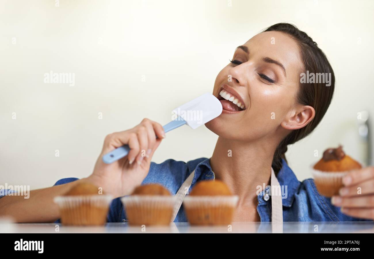 Solo un tocco di bontà zuccherata. Una giovane donna felice che lecca una spatola gelata Foto Stock