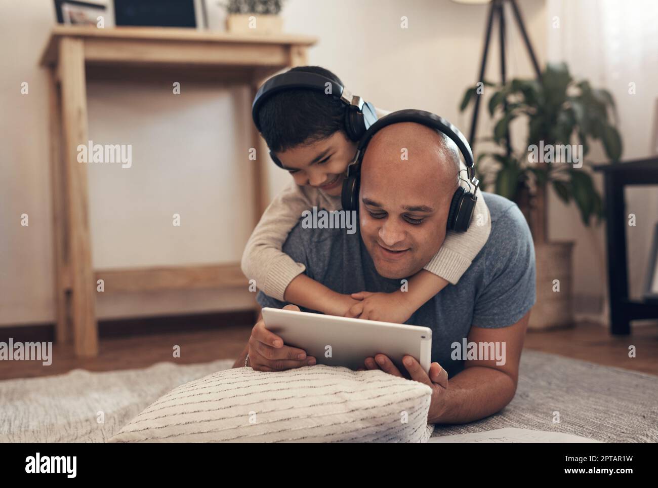 Le famiglie che imparano insieme crescono insieme. un adorabile ragazzino che usa un tablet digitale e le cuffie con il padre a casa Foto Stock