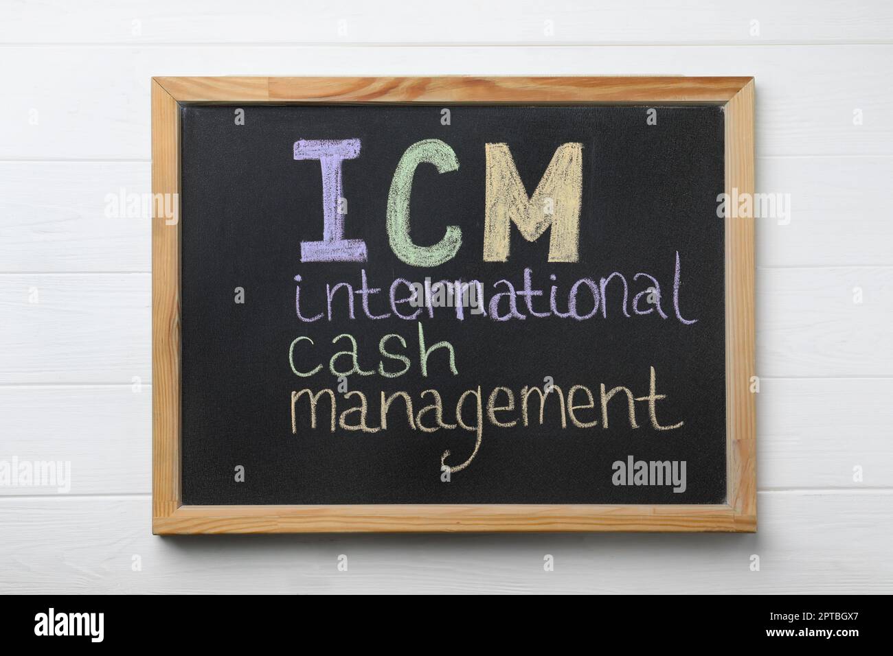Piccola lavagna con l'abbreviazione ICM (International Cash Management) su sfondo di legno bianco, vista dall'alto Foto Stock