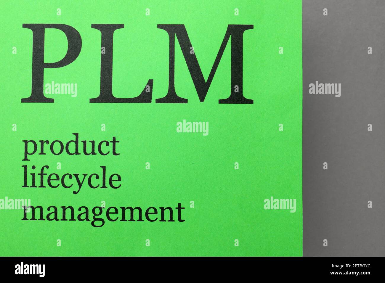 Libro verde con abbreviazione PLM (Product Lifecycle Management) su sfondo grigio, vista dall'alto Foto Stock