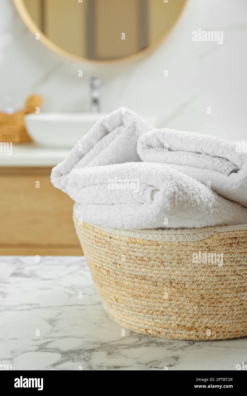 Cestino in vimini con asciugamani piegati su tavolo in marmo bianco in bagno  Foto stock - Alamy