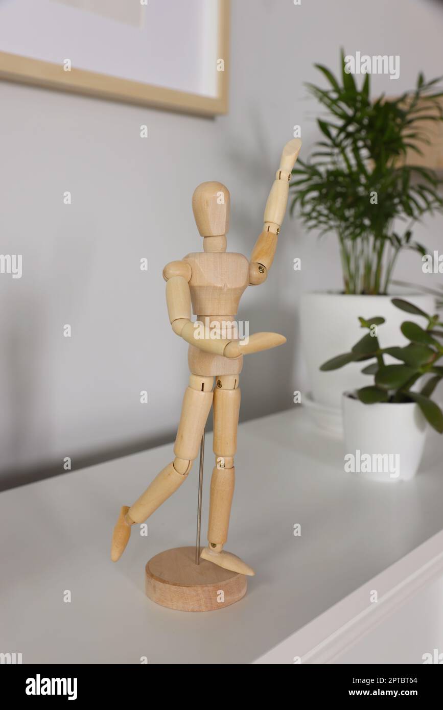 Elegante statuina di legno vicino alle piante di casa su un tavolo bianco all'interno Foto Stock