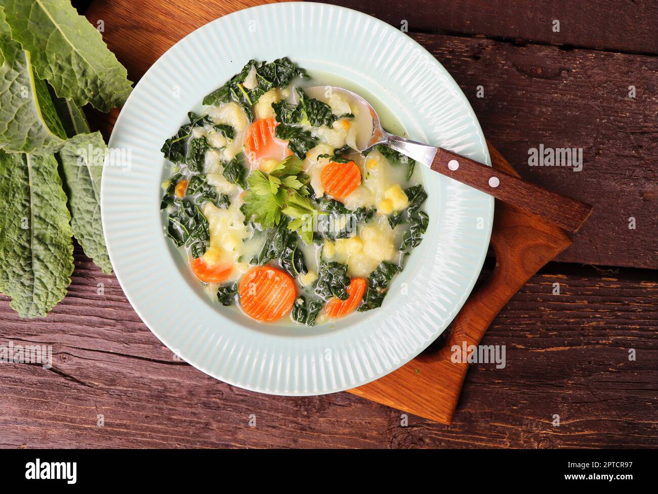 Sana zuppa di verdure con kale. Vista dall'alto tavolo scena su uno sfondo di legno scuro. Foto Stock