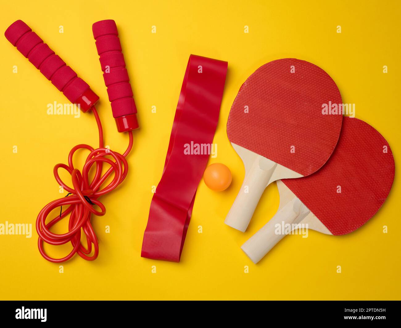 Racchetta da tennis in legno per ping pong e palla di plastica su sfondo giallo, vista dall'alto Foto Stock