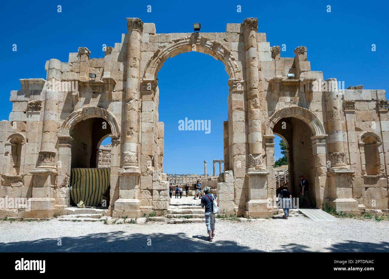 I turisti camminano attraverso un arco della porta Sud presso l'antico sito di Jerash in Giordania. Foto Stock