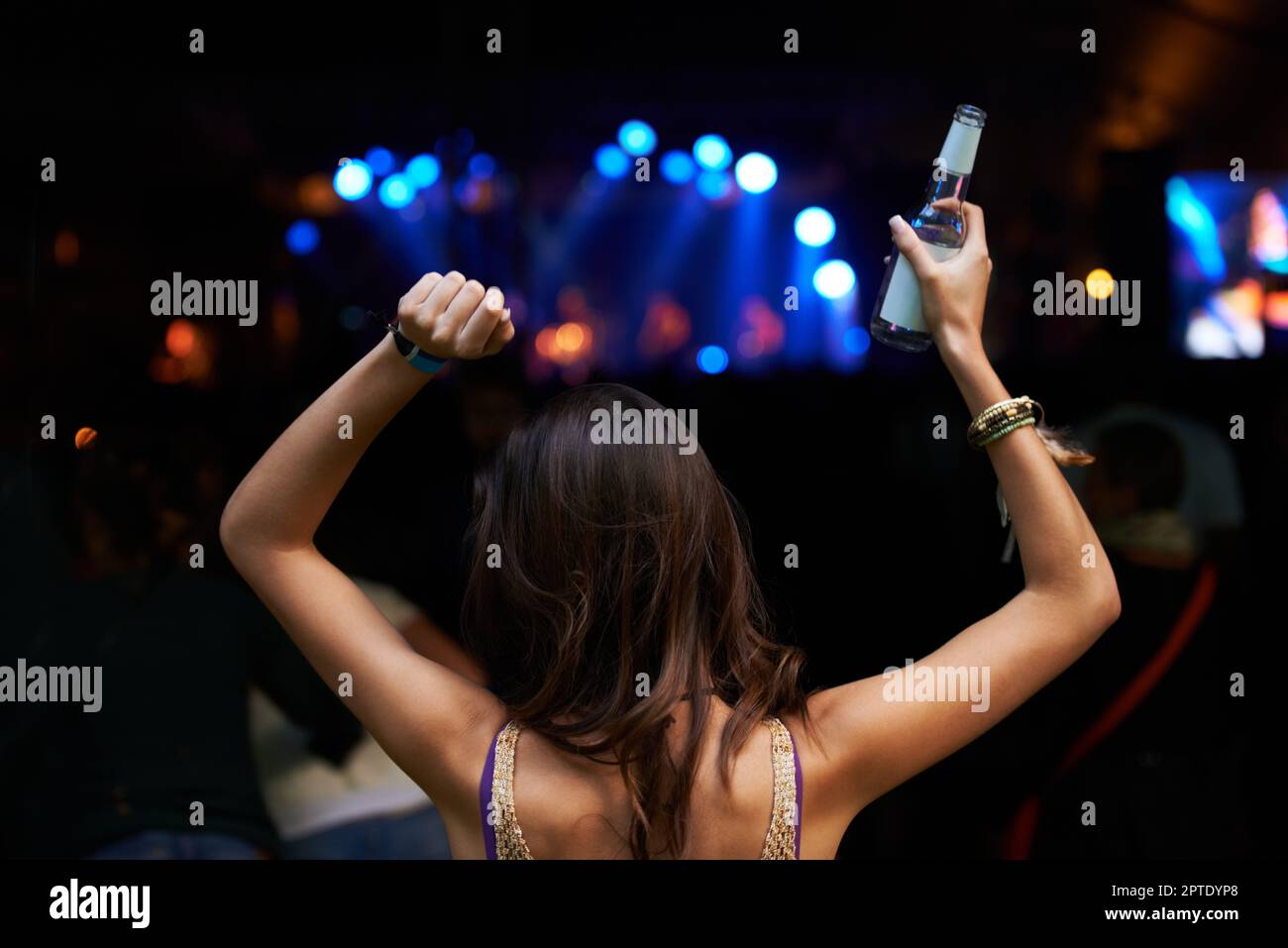 Lasciare che la musica la porta via. Vista posteriore di una donna che festeggiava con una band sul palco in un festival musicale all'aperto Foto Stock