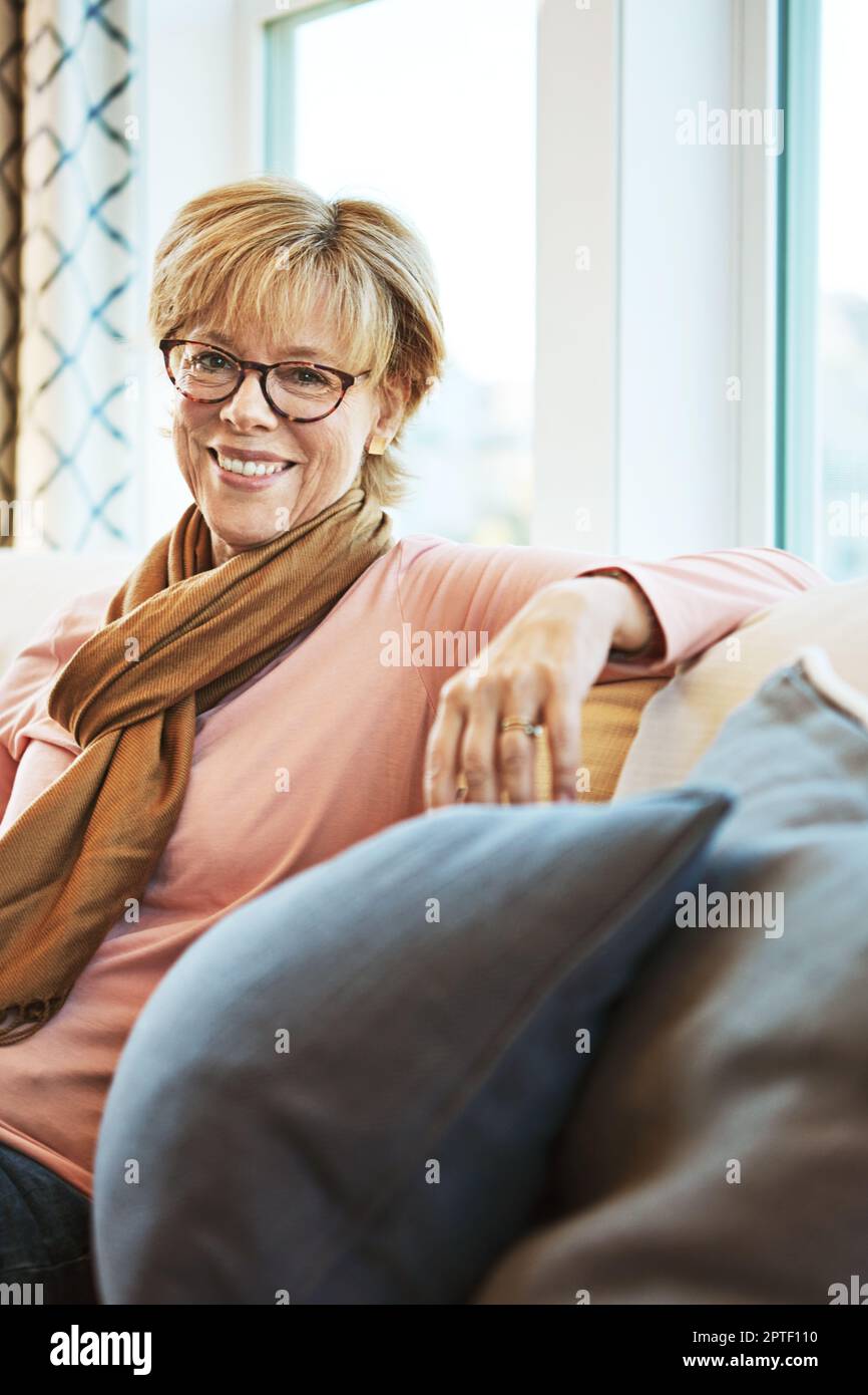 Non ho potuto chiedere un pensionamento migliore. Ritratto di una donna felice e matura che si rilassa sul divano di casa. Foto Stock