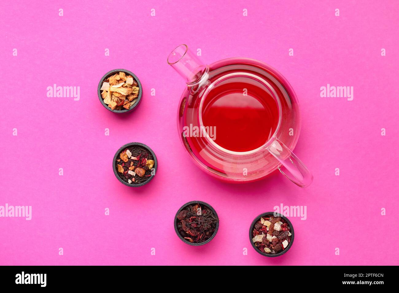 Composizione con bicchiere di tè e diverse miscele di frutta secca su fondo rosa Foto Stock
