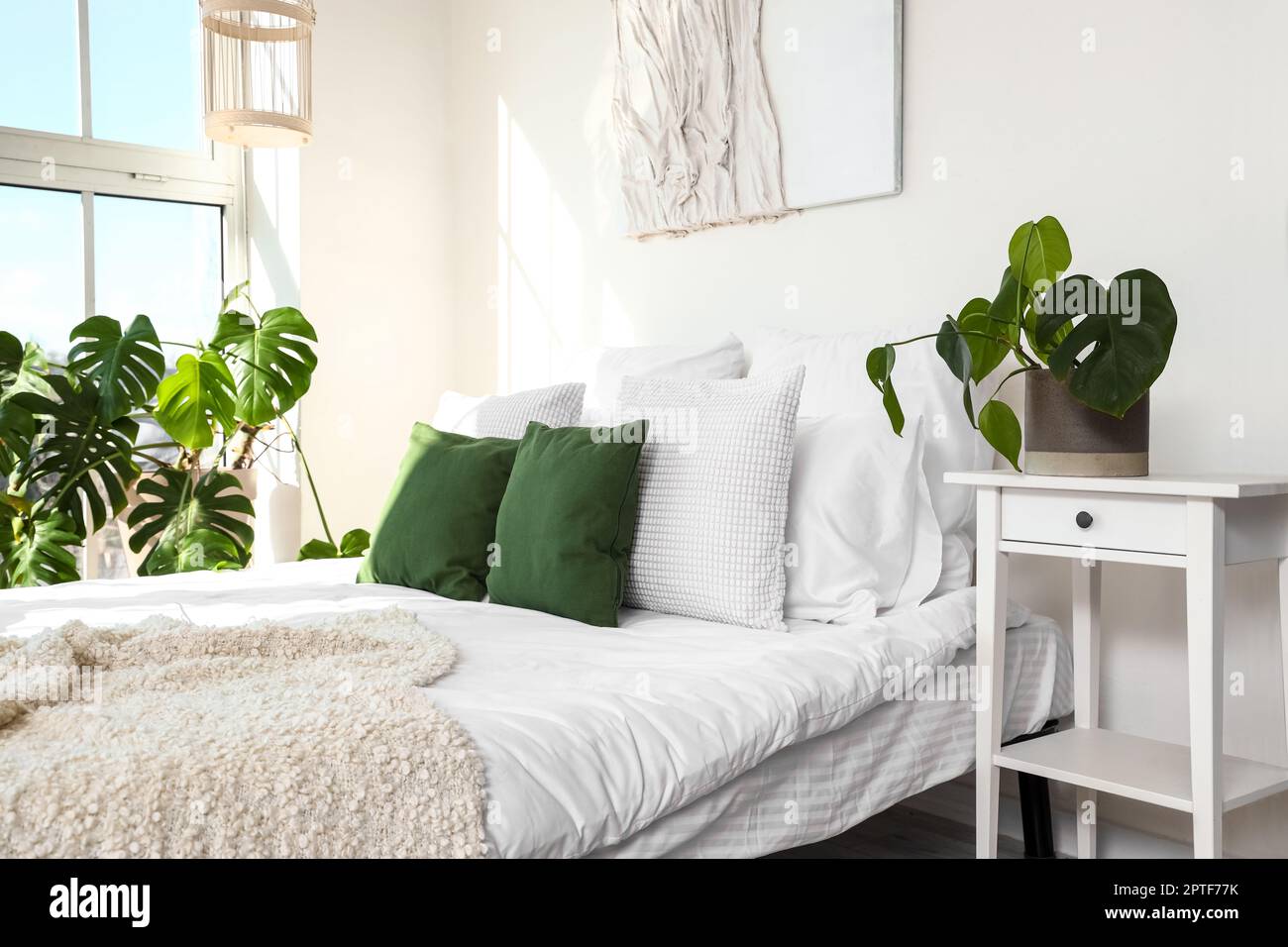 Interno di camera da letto chiara con pianta di Monstera e letto Foto stock  - Alamy