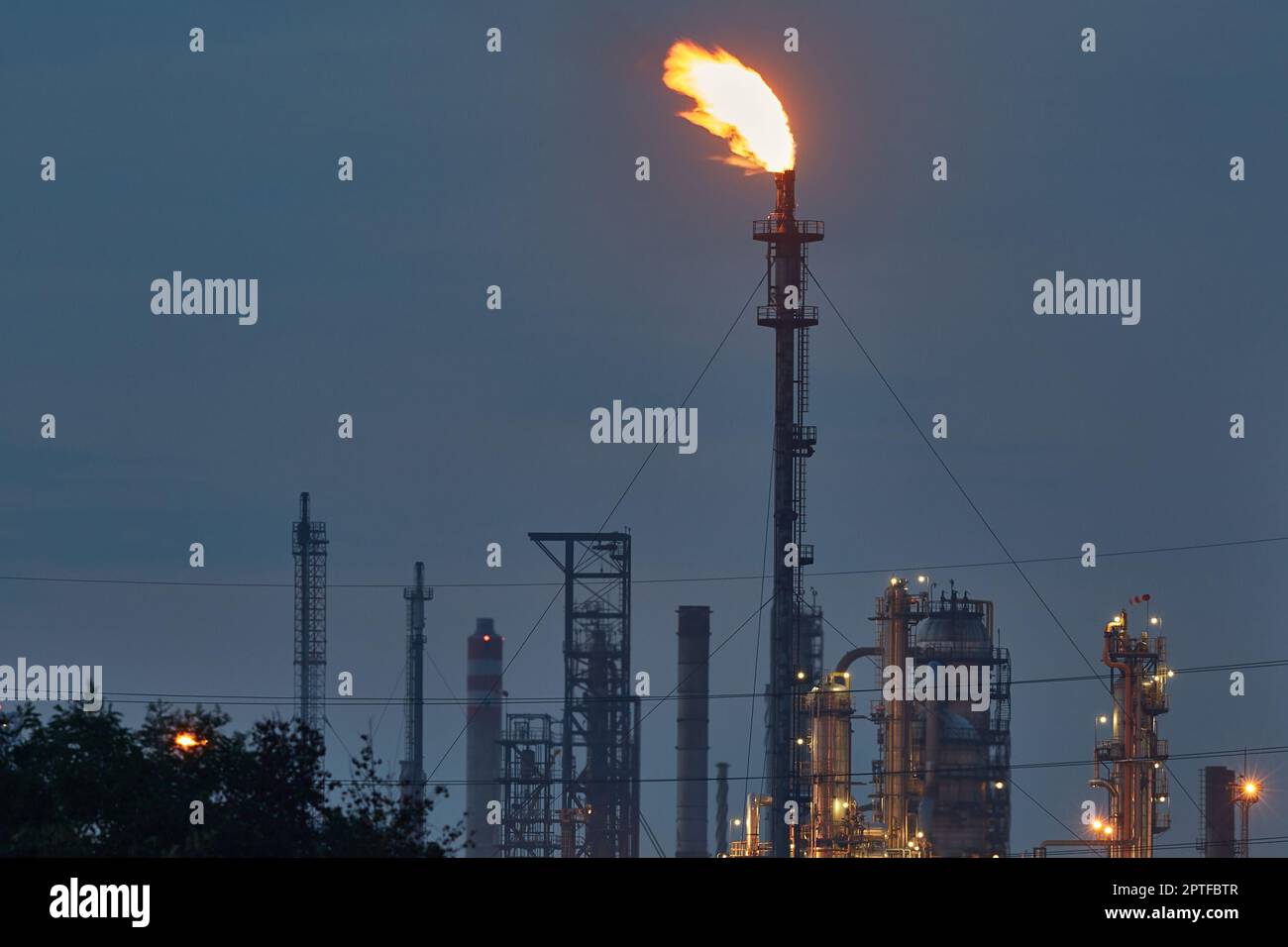 Ugello della torcia a fiamma di una raffineria di petrolio al buio che brucia il gas in eccesso Foto Stock
