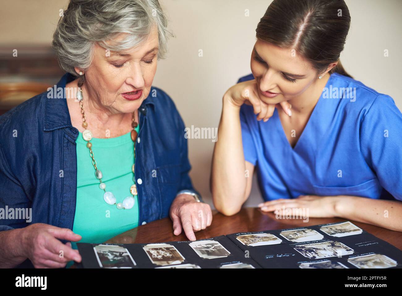 Questo mi riporta indietro... un residente e un'infermiera che guarda attraverso un album fotografico Foto Stock