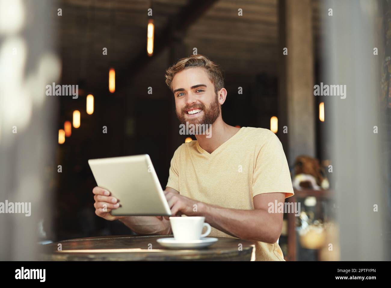 È il mio caffè preferito per godersi un po' di navigazione. Ritratto di un giovane uomo che usa un tablet digitale in un bar Foto Stock