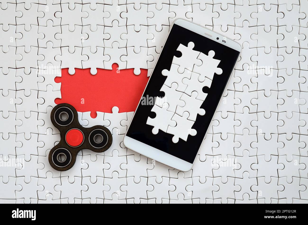 Una moderna grande smartphone con un touch screen e un filatore giacciono su un bianco puzzle in uno stato assemblato con gli elementi mancanti Foto Stock