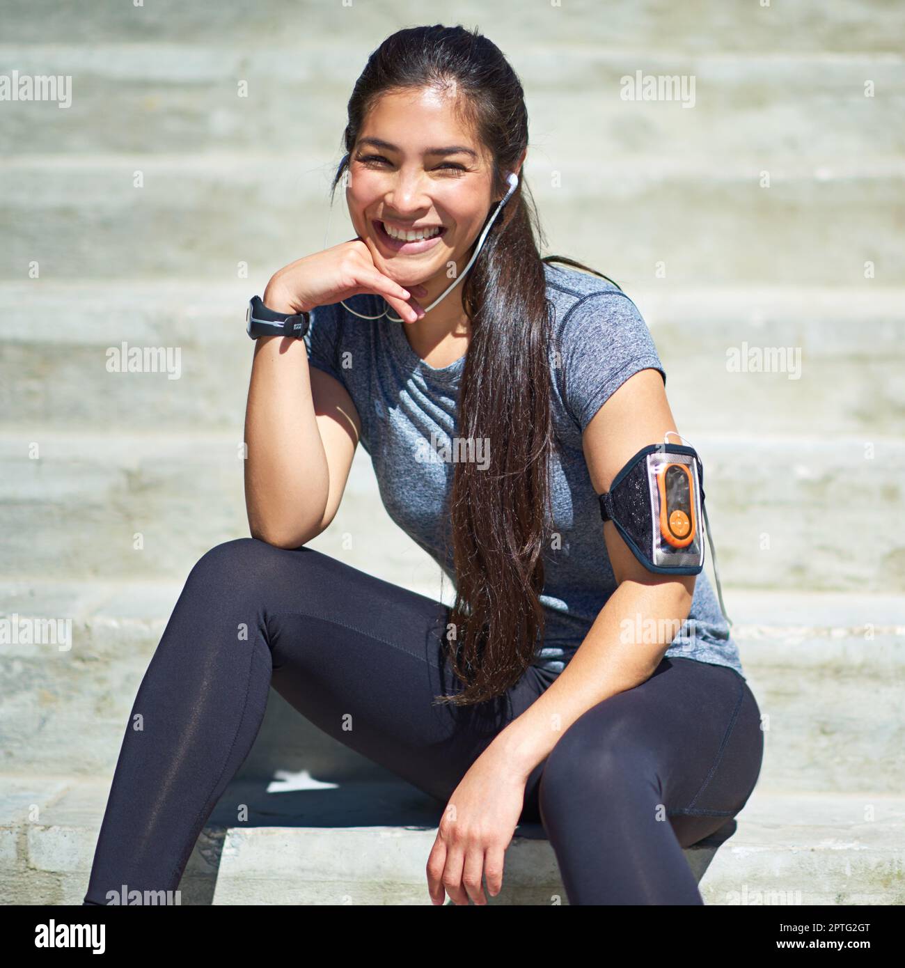 Sano e felice: Tutto ciò che conta. una giovane donna sportiva che ascolta la musica mentre si siede sui gradini all'aperto Foto Stock