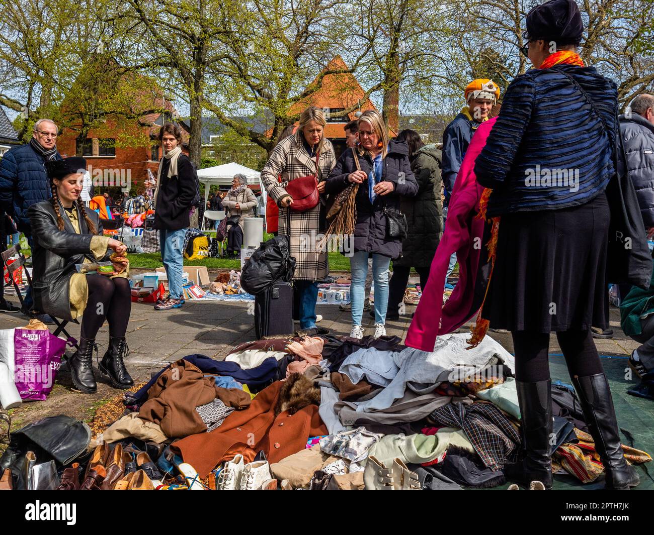 Amsterdam, Paesi Bassi. 27th Apr, 2023. Si vedono due donne che guardano una stalla piena di vestiti di seconda mano. Il giorno del Re è rinomato per essere uno dei festeggiamenti più grandi e colorati del paese, specialmente ad Amsterdam. La città è piena di arancione, mentre la gente si diverte a fare la festa di strada più grande dell'anno, godendosi i mercati liberi e divertendosi sulle barche lungo i canali. Credit: SOPA Images Limited/Alamy Live News Foto Stock