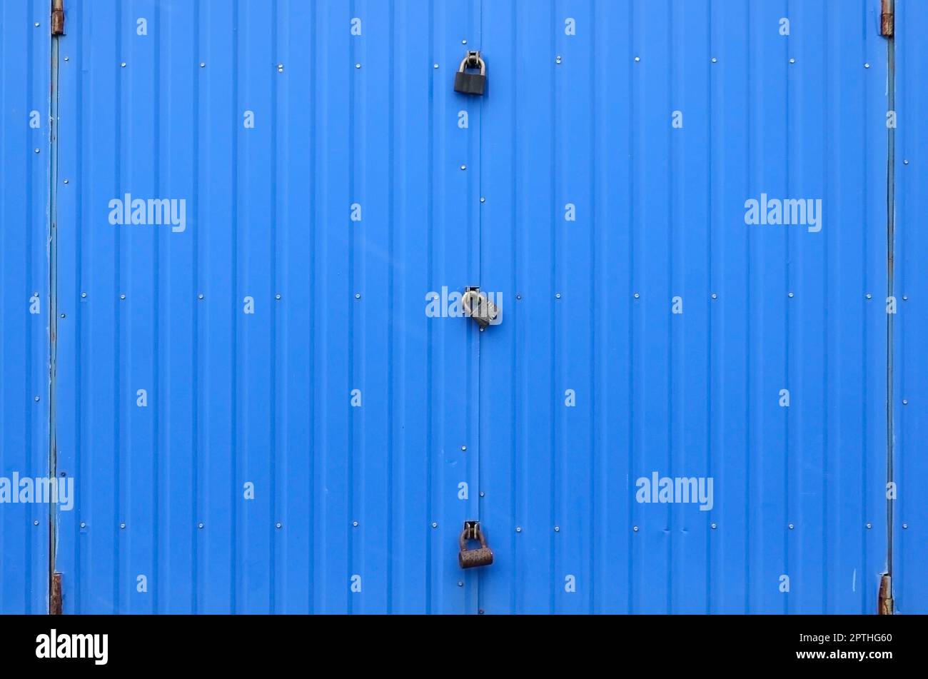 Struttura di una parete blu metallica con un cancello chiuso per tre serrature Foto Stock