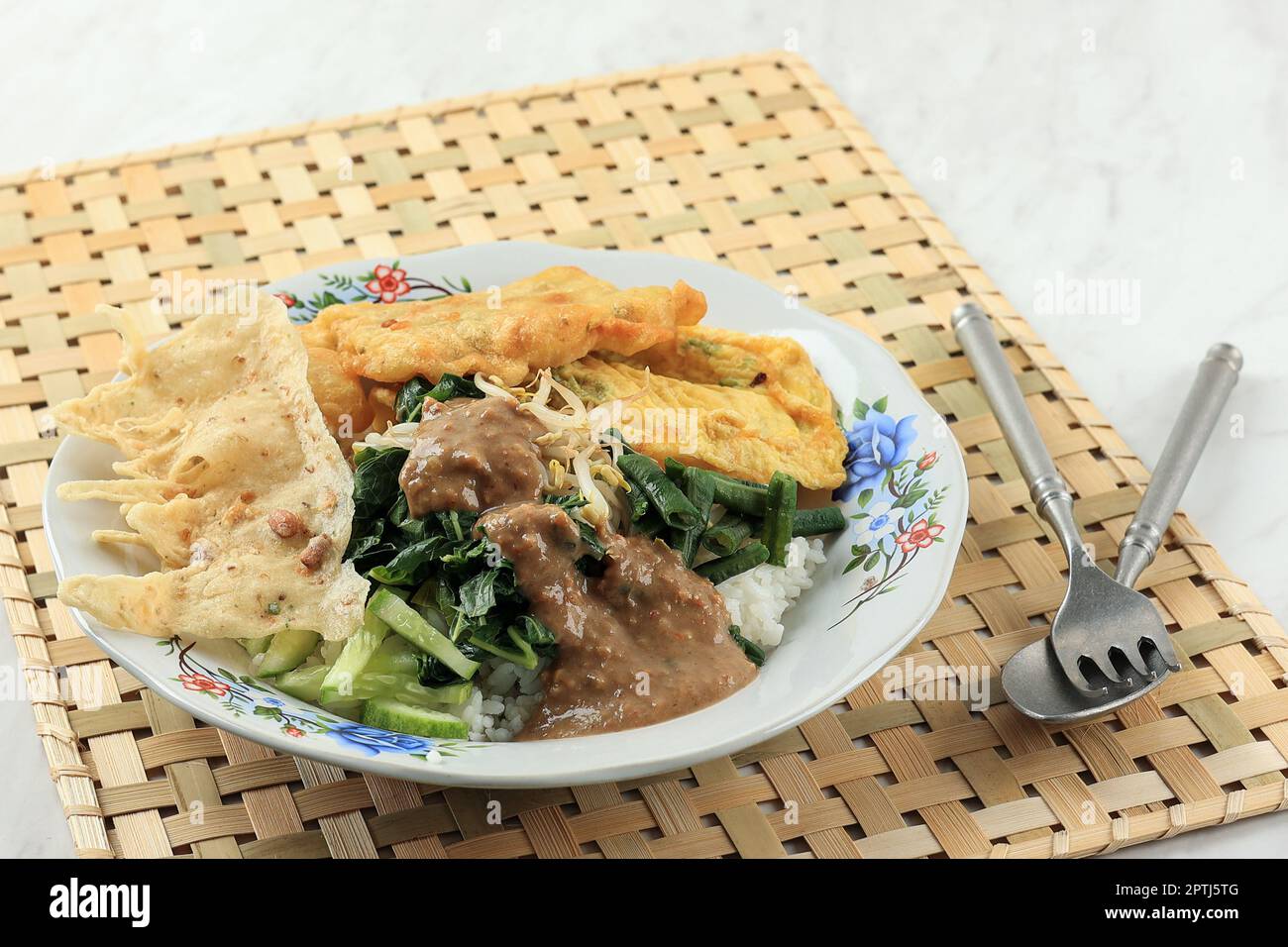 Nasi Pecel Madiun, riso bianco al vapore con verdure bollite, Peyek, tempeh, condito con salsa di arachidi piccante. Popolare menu indonesiano per la colazione Foto Stock