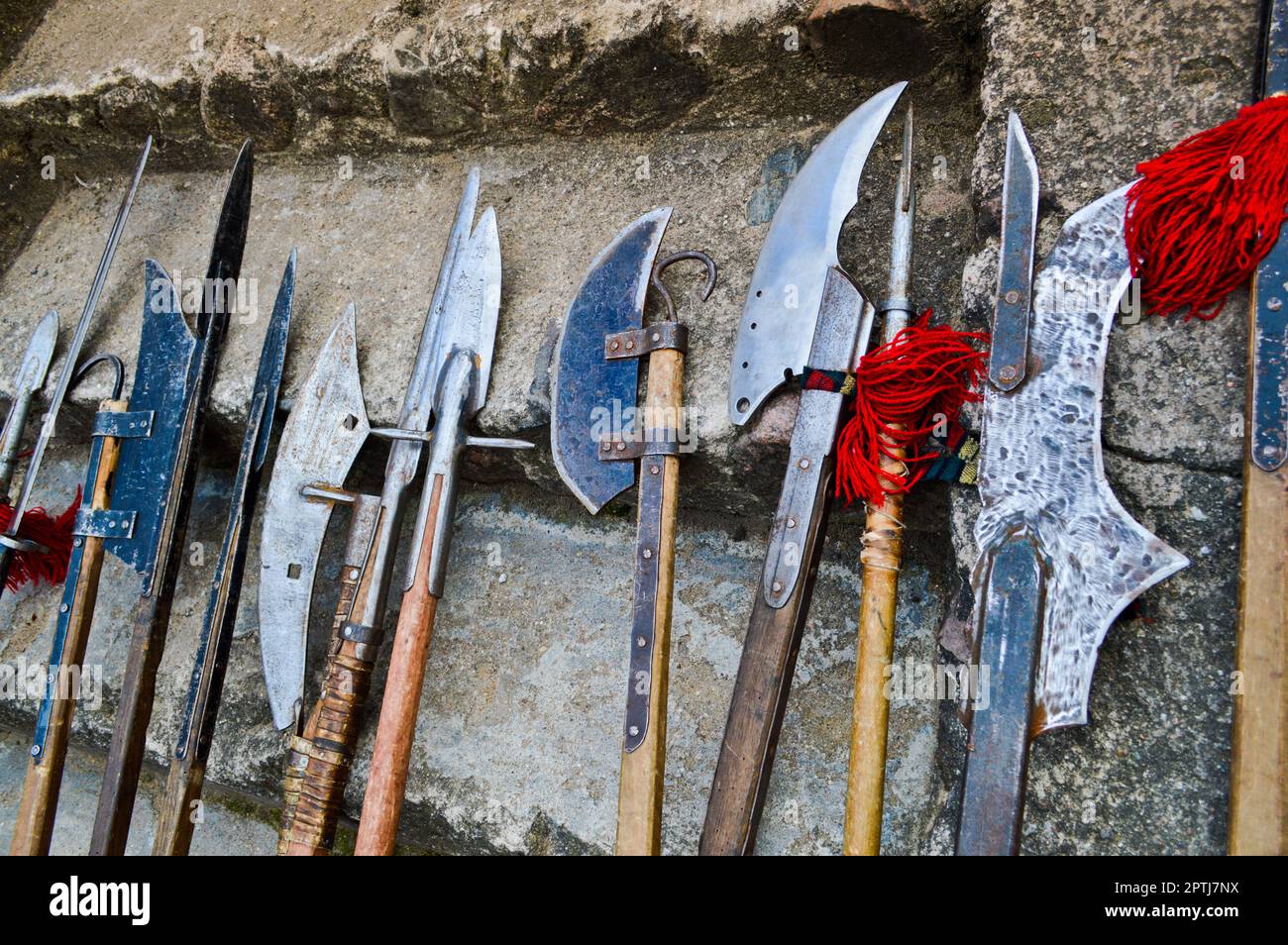 Le vecchie armi fredde medievali, assi, olibardi, coltelli, spade con manici in legno lecca i gradini in pietra del castello. Foto Stock