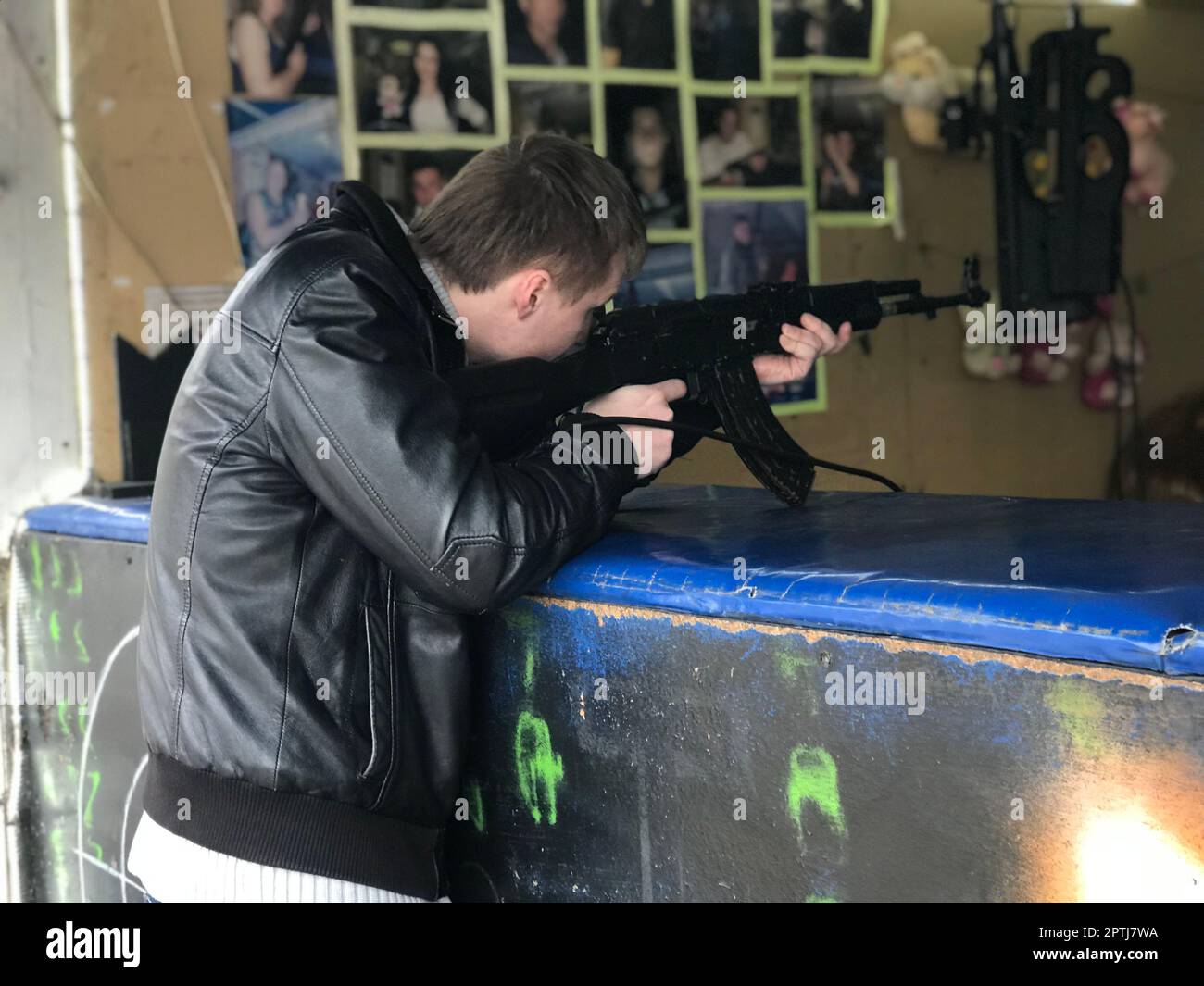 Un giovane civile in una giacca di pelle nera spara un fucile d'assalto Kalashnikov nero Foto Stock