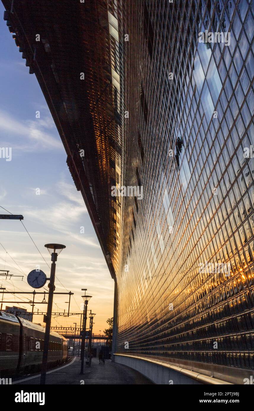 Stazione ferroviaria alle ore dorate con retrogusto riflesso sulla facciata di vetro di un edificio Foto Stock