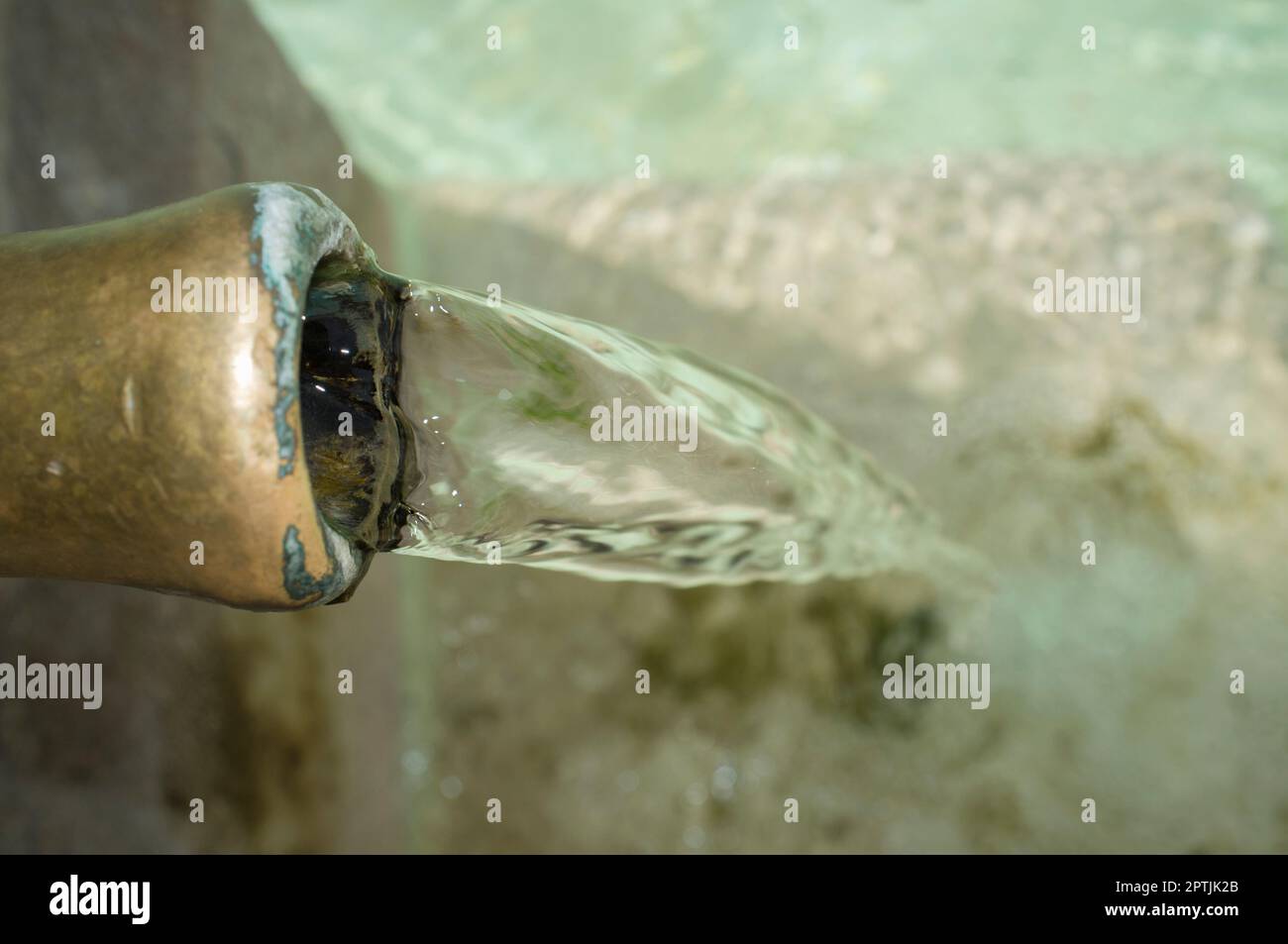 Acqua che fluisce permanentemente da un tubo di una fontana pubblica. Concetto di approvvigionamento di acqua potabile in tempi antichi Foto Stock