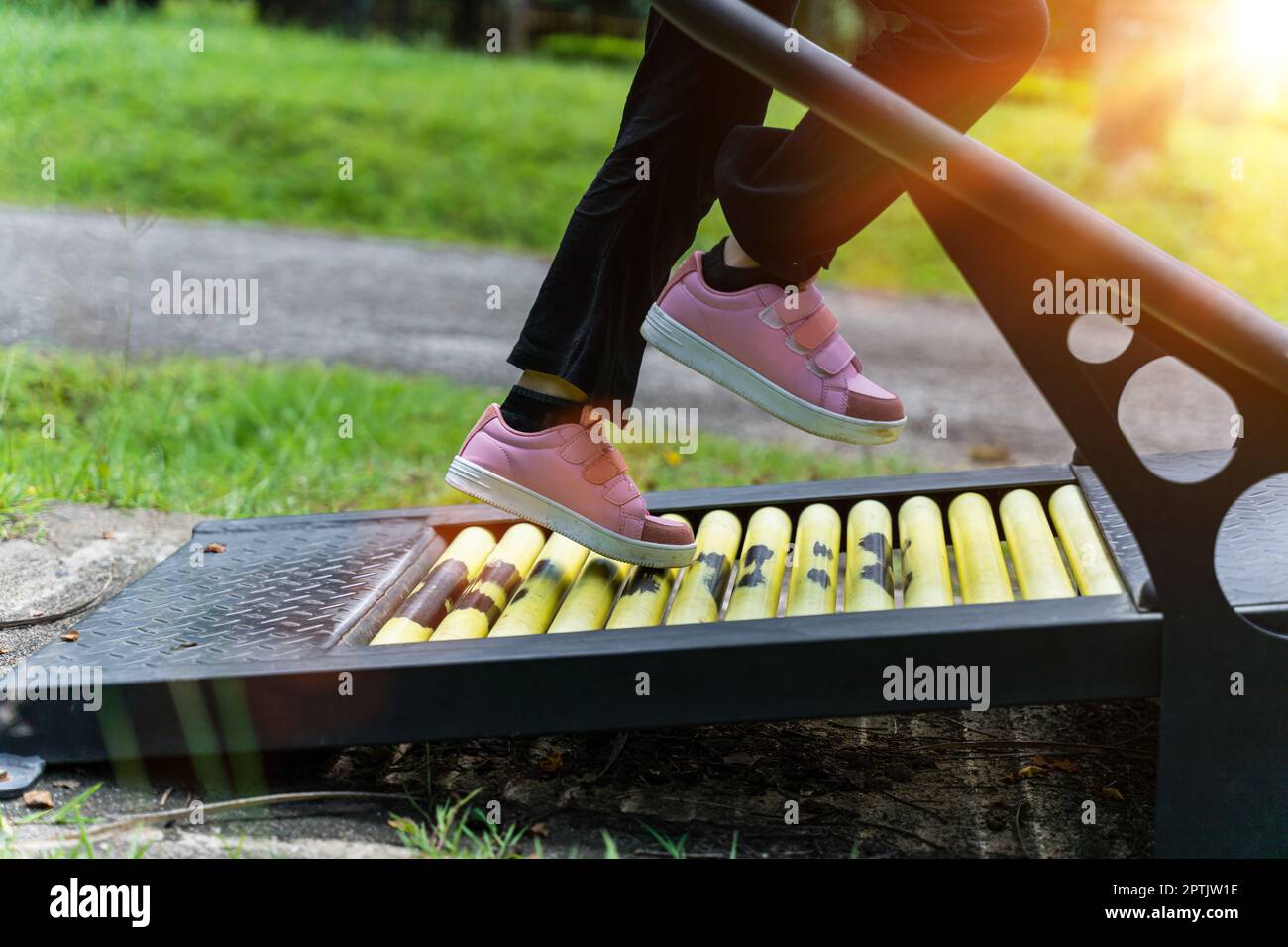 Primo piano di una bambina che corre su un tapis roulant per allenarsi nel parco giochi all'aperto. Concetto di fitness e stile di vita sano Foto Stock