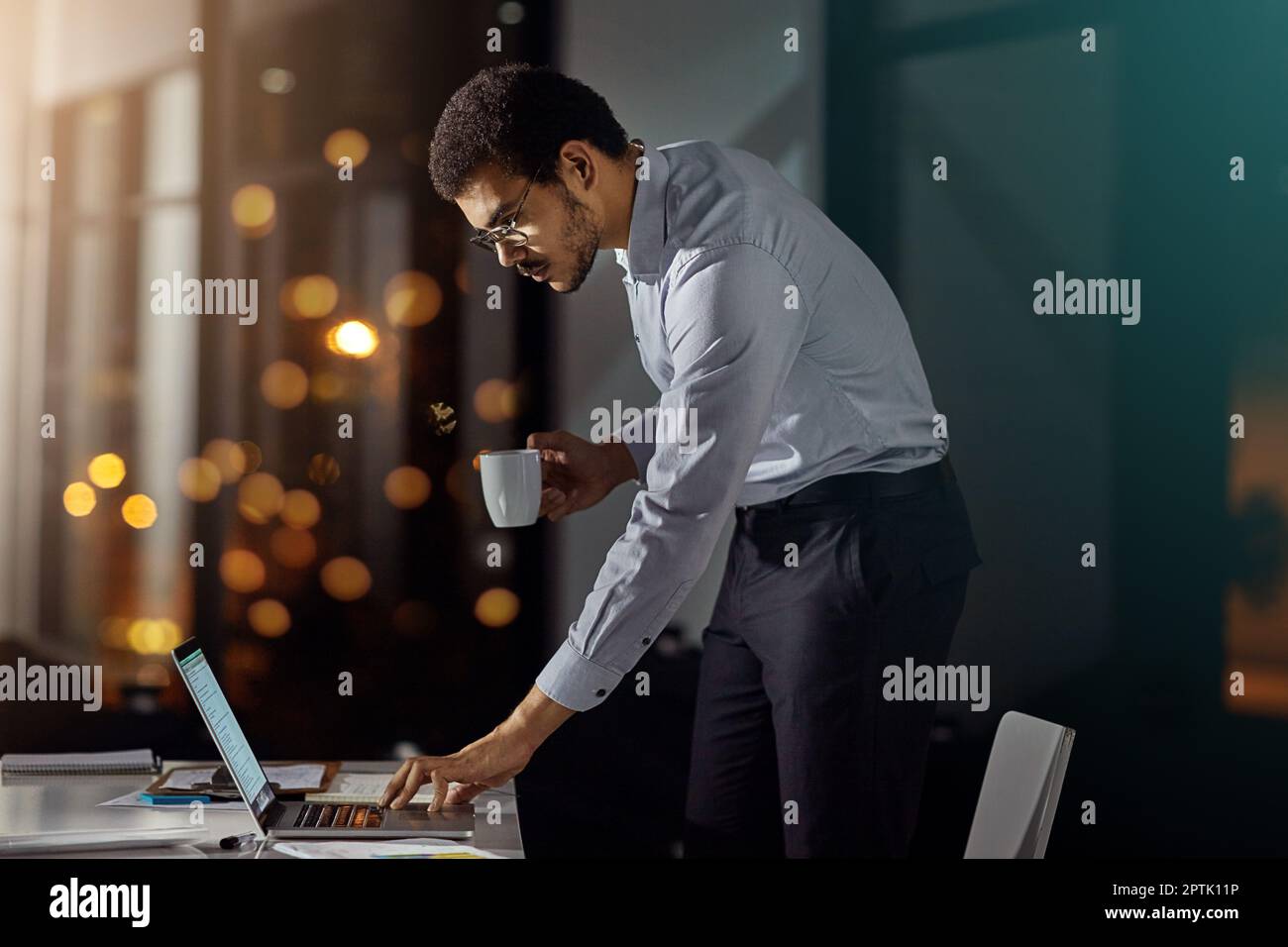 Primo, ultimo a partire. Ora thats impegno. un uomo d'affari che utilizza un computer portatile mentre si sta a letto tardi in ufficio. Foto Stock