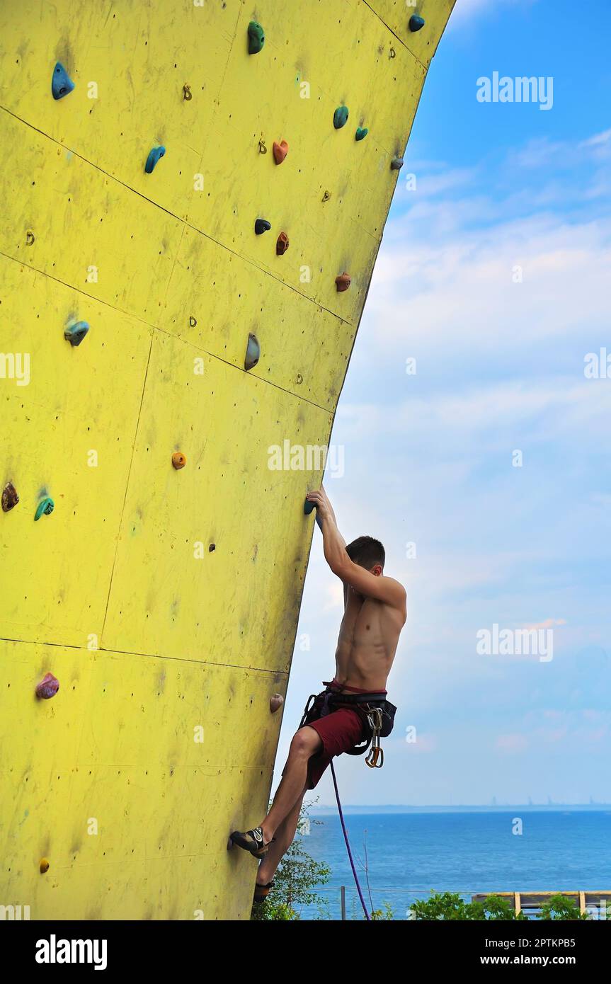Giovane uomo arrampicata su una parete Foto Stock