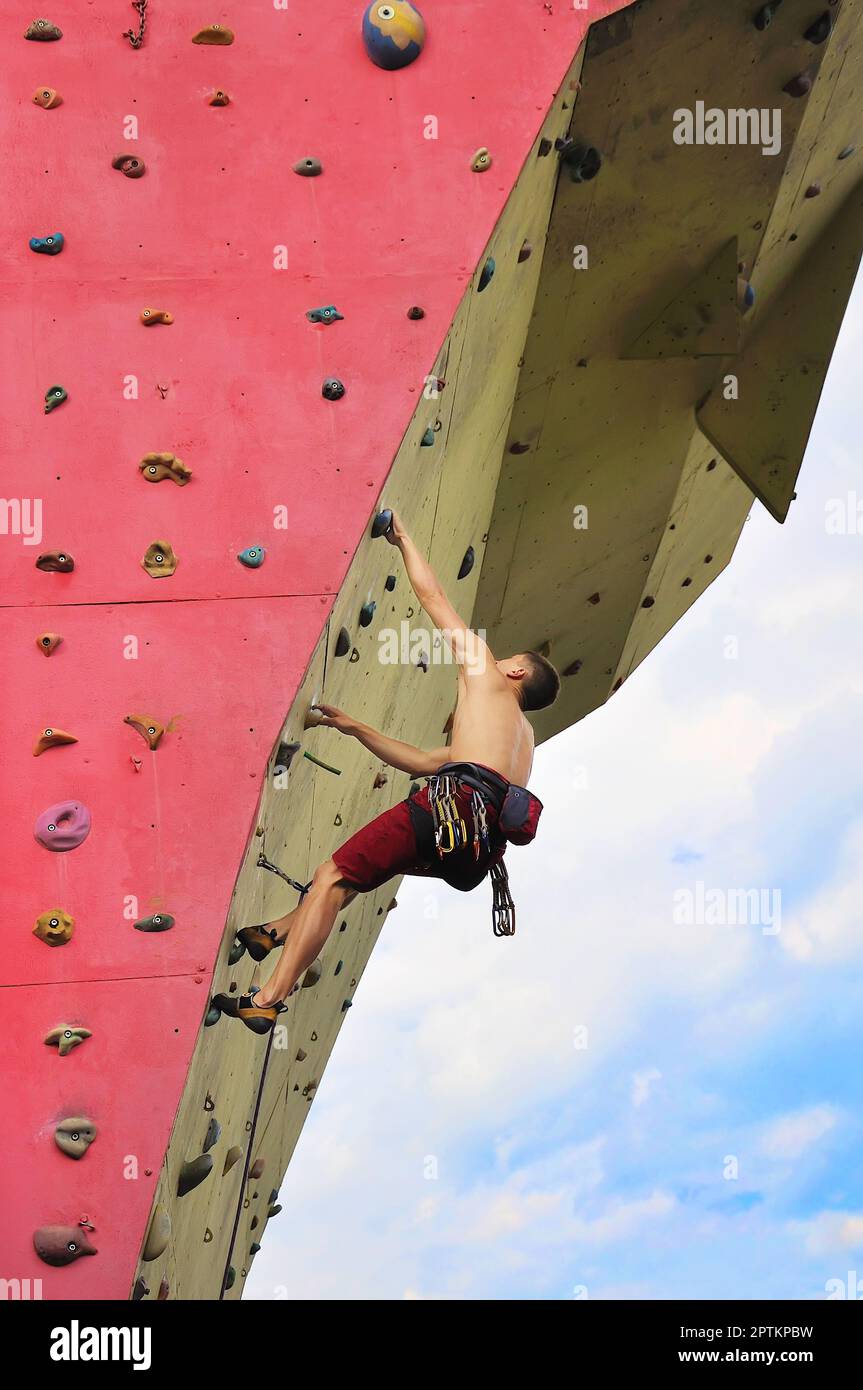 Uomo muscoloso che si arrampica su una grande parete Foto Stock
