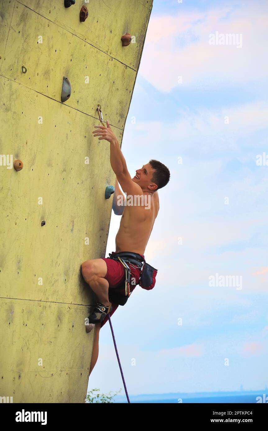 Uomo scalatore muscolare che si arrampica su un muro Foto Stock