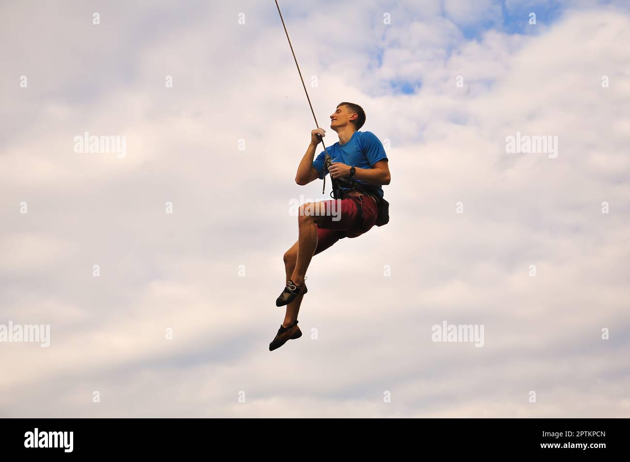 Arrampicatore appeso su una corda sullo sfondo del cielo Foto Stock
