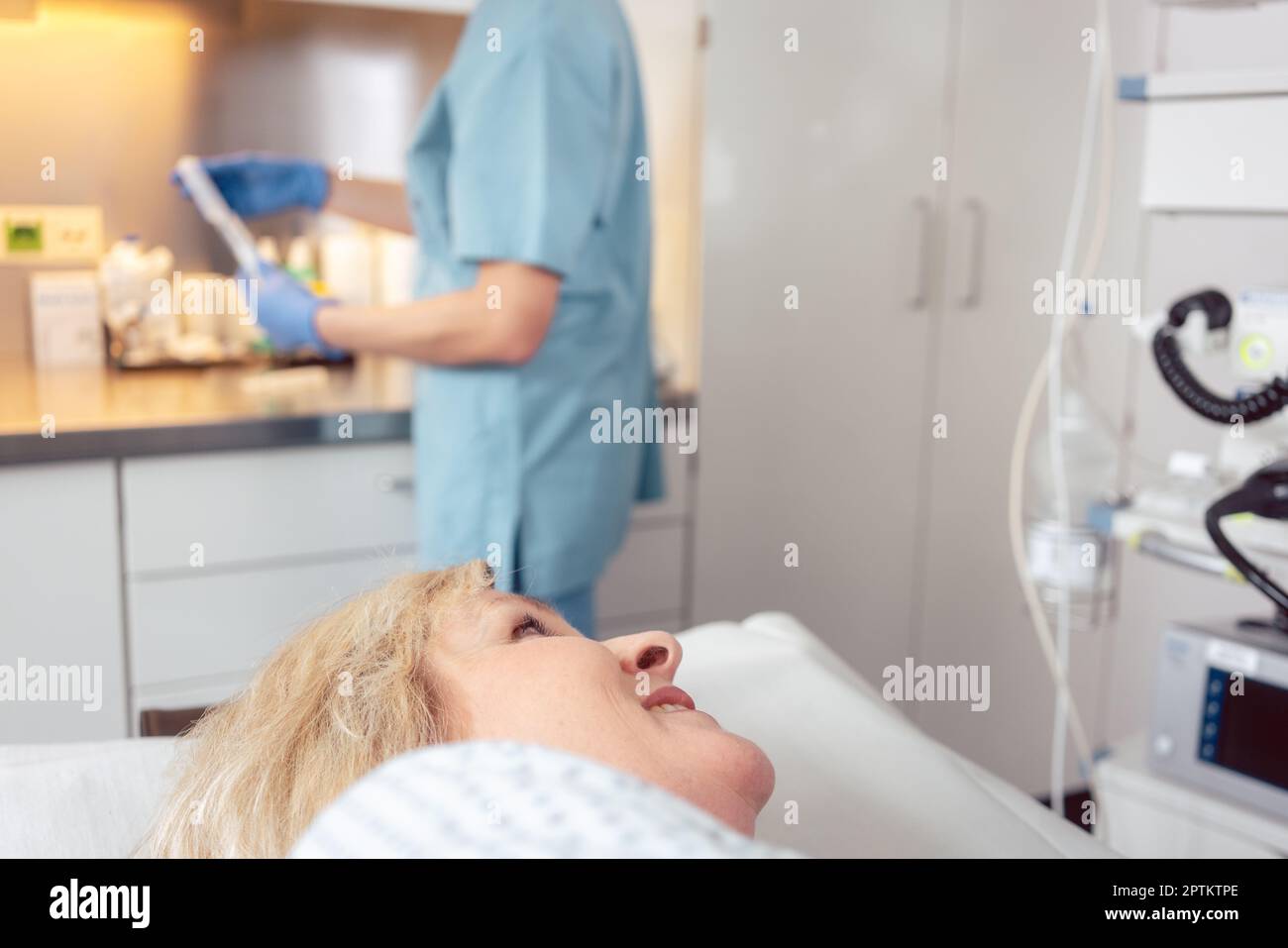 Paziente donna in ospedale che guarda infermieri che si preparano per l'intervento chirurgico Foto Stock
