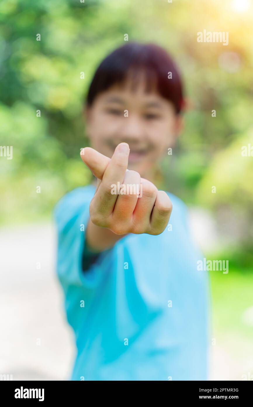 Una bella bambina che fa e mostra mini segno mano cuore. Simbolo dell'amore con le dita Foto Stock