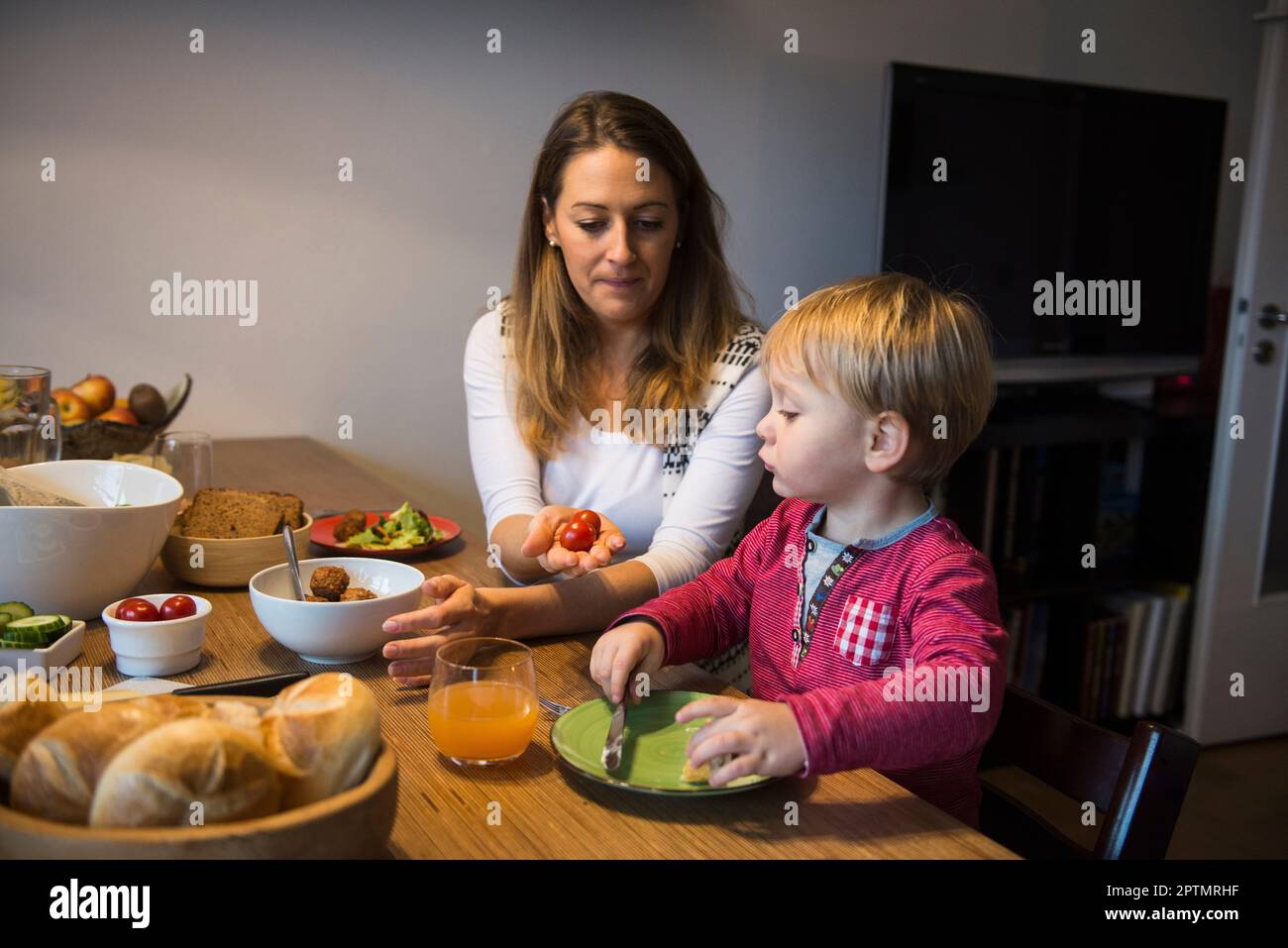 Madre che offre pomodori ciliegini al suo piccolo figlio, Monaco, Germania Foto Stock