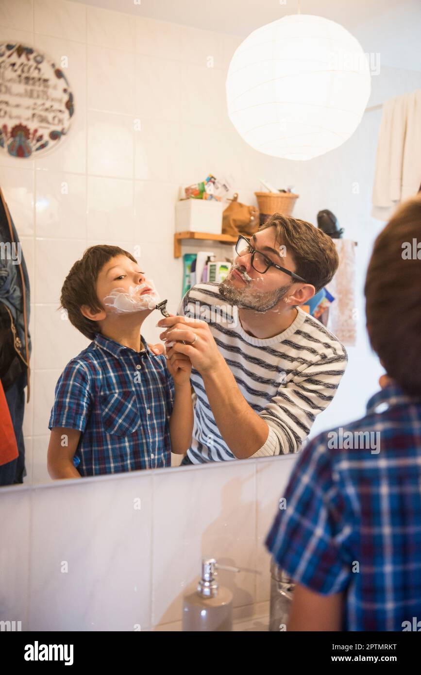 Padre che assiste suo figlio a radersi in bagno, Monaco, Germania Foto Stock