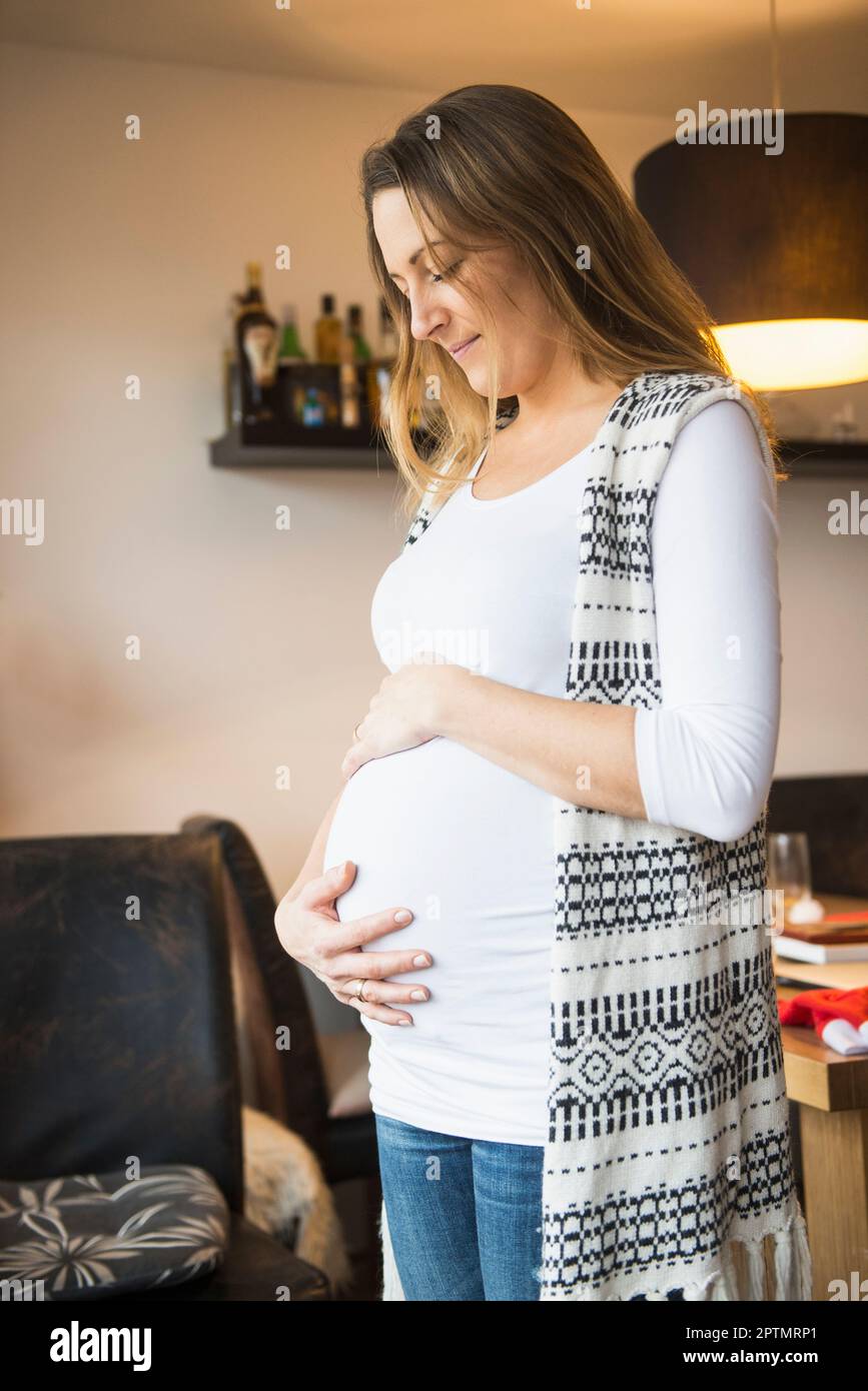 Donna incinta che guarda giù il suo ventre, Monaco, Germania Foto Stock