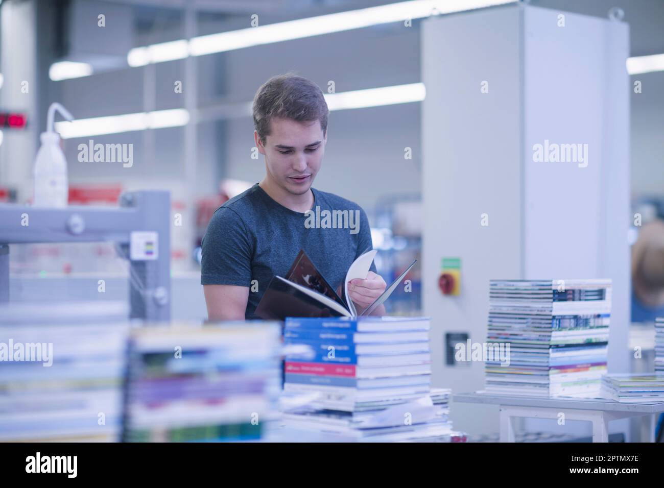 Giovane uomo che lavora nel settore della stampa di libri, Brembarten, Hartheim am Rhein, Baden-Wuerttemberg, Germania Foto Stock