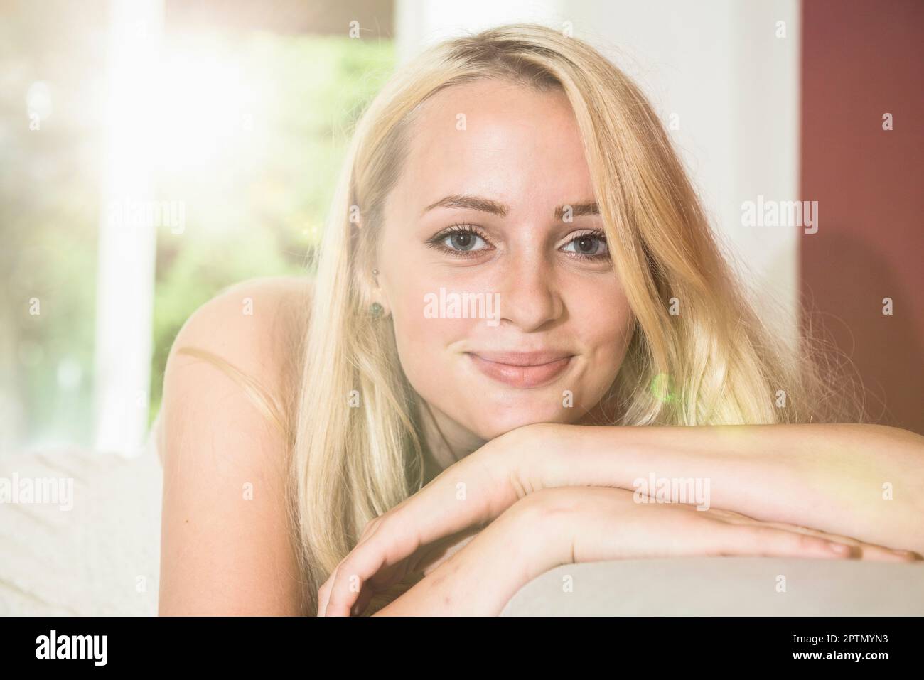Ritratto di una bella giovane donna che si rilassa sul divano nel soggiorno di Monaco, Baviera, Germania Foto Stock