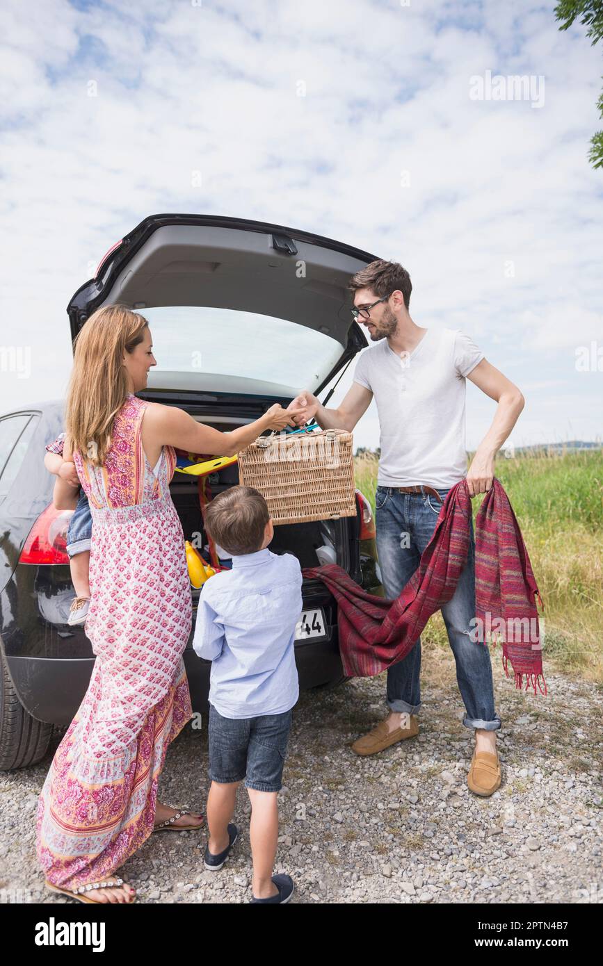 Famiglia scaricare l'auto su prato in campagna, Baviera, Germania Foto Stock