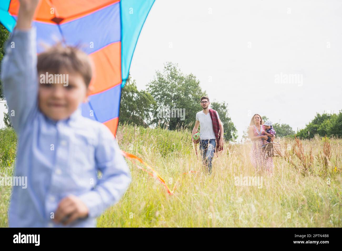 Famiglia a piedi sul prato con cestino pic-nic e aquilone in campagna, Baviera, Germania Foto Stock