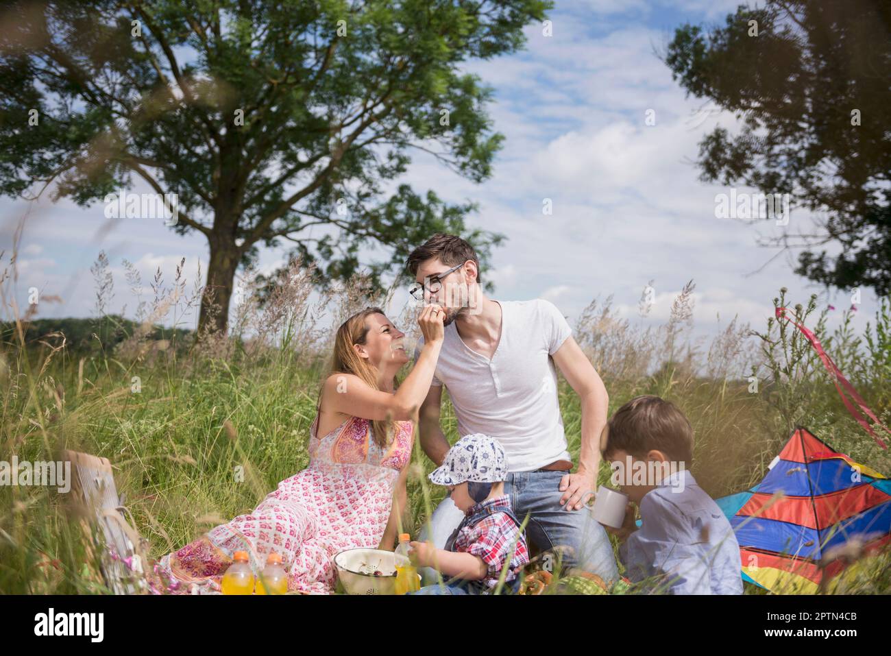 Donna che alimenta la ciliegia al marito su un prato in campagna, Baviera, Germania Foto Stock