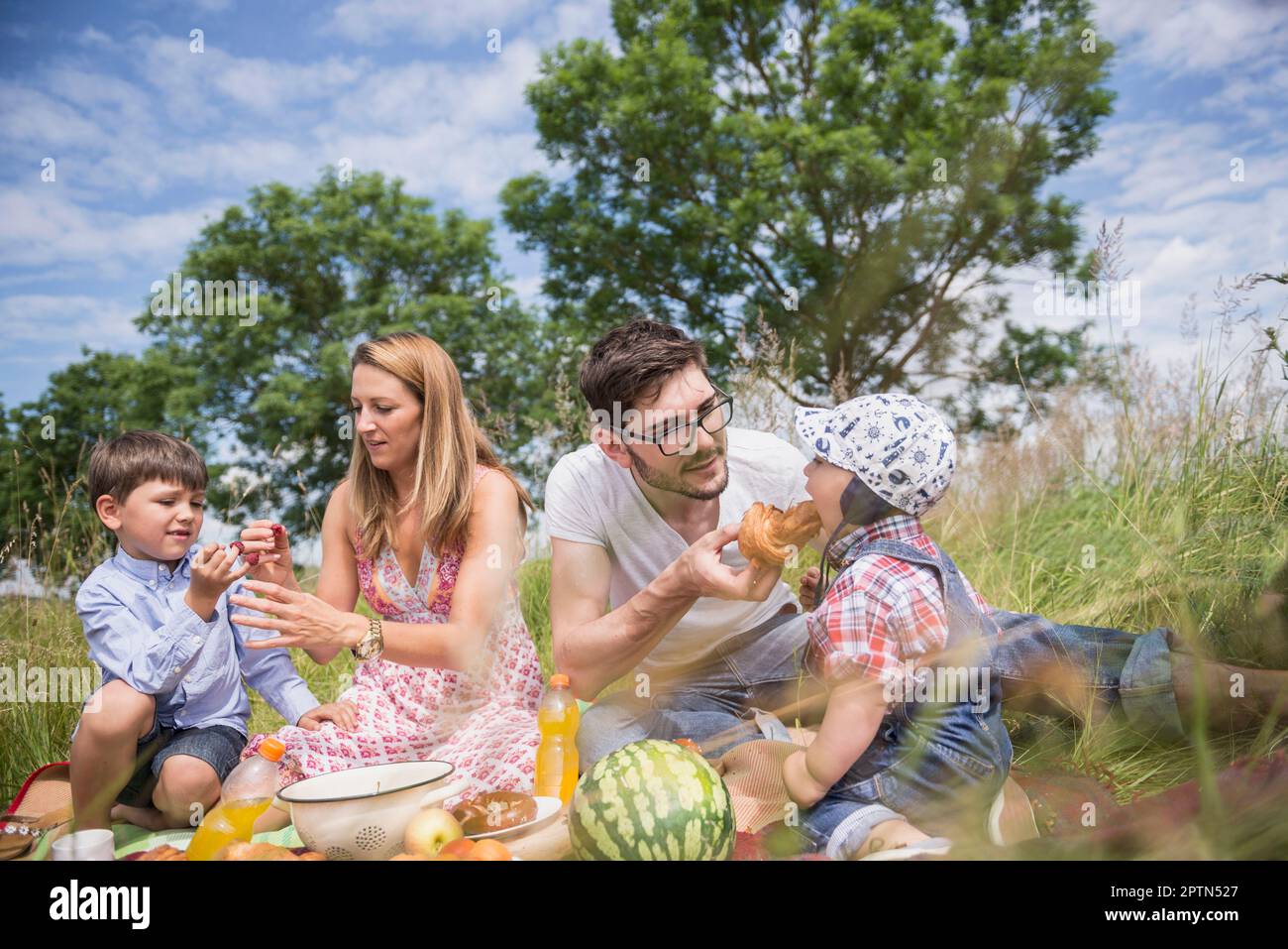 I genitori mangiano i loro figli in un pic-nic sul prato in campagna, Baviera, Germania Foto Stock