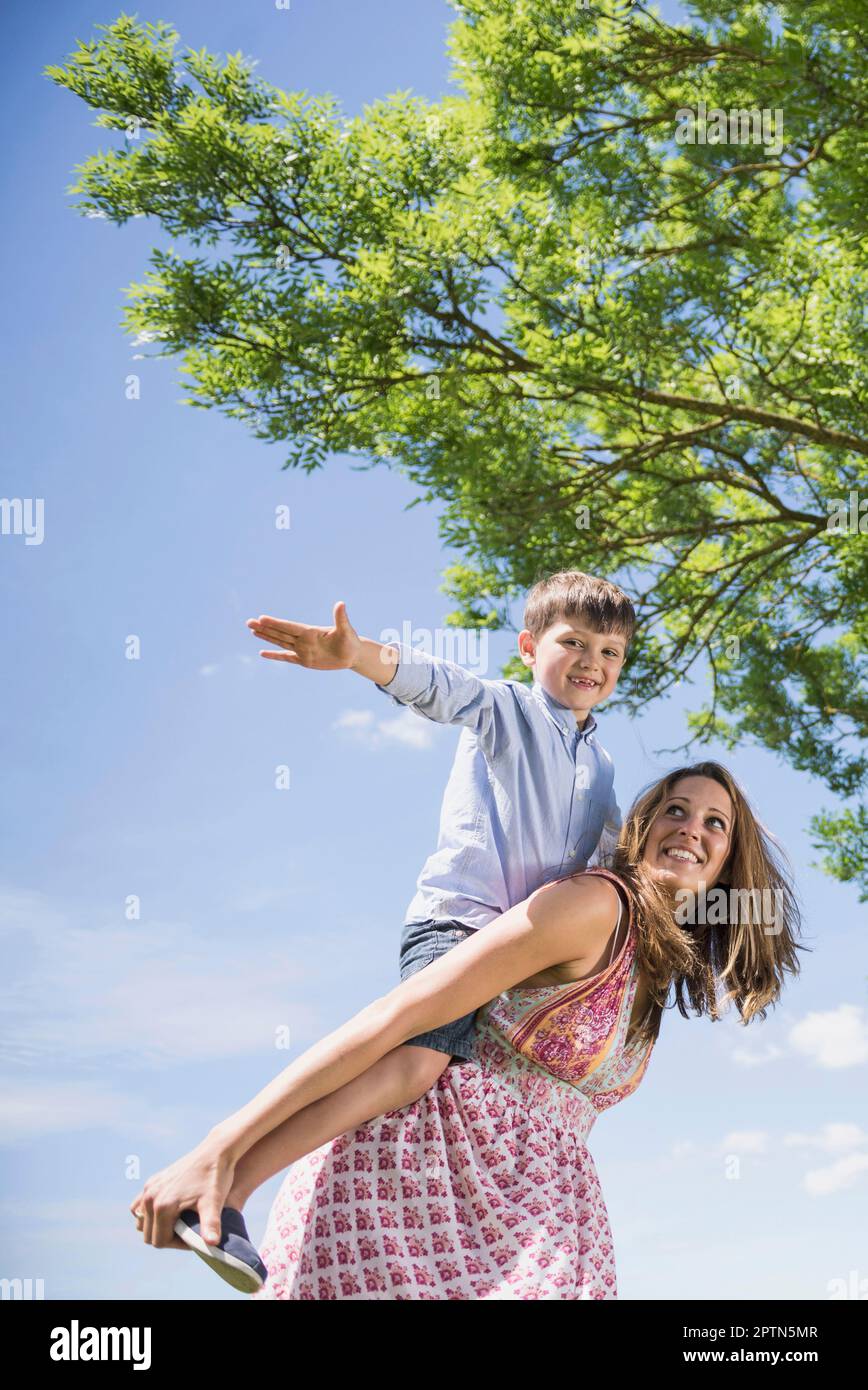 Ragazzo felice godendo piggyback cavalcata sulla madre a picnic, Baviera, Germania Foto Stock