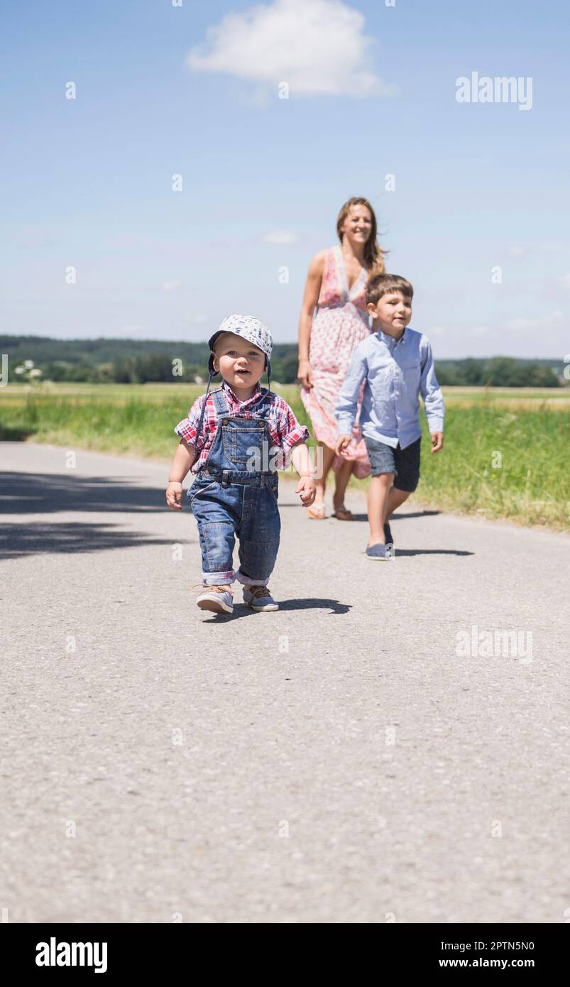 Donna con il figlio che cammina sulla strada in campagna, Baviera, Germania Foto Stock