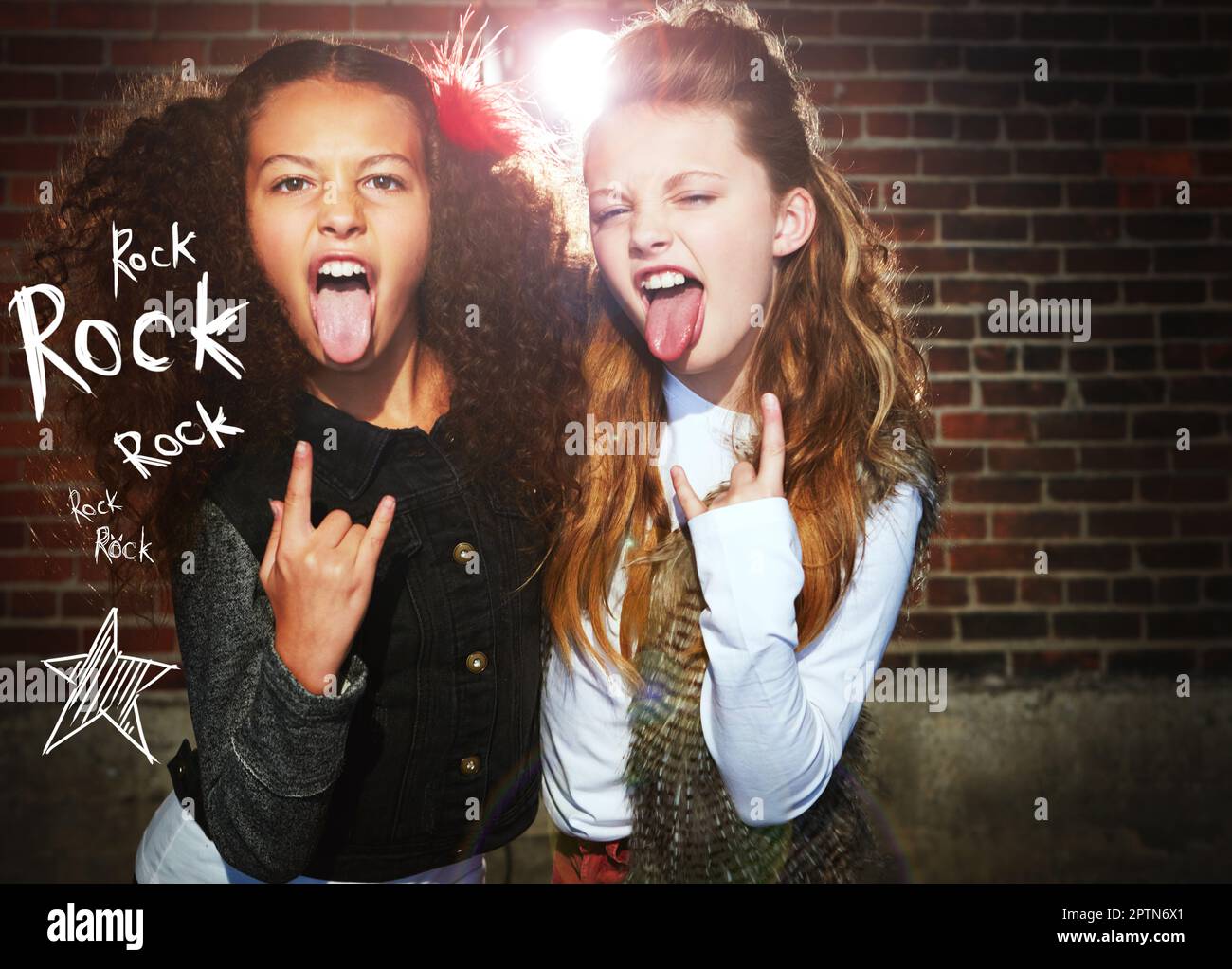 Ci piace il Rock n Roll. due ragazze che tirano i volti e fanno un gesto rock. Foto Stock