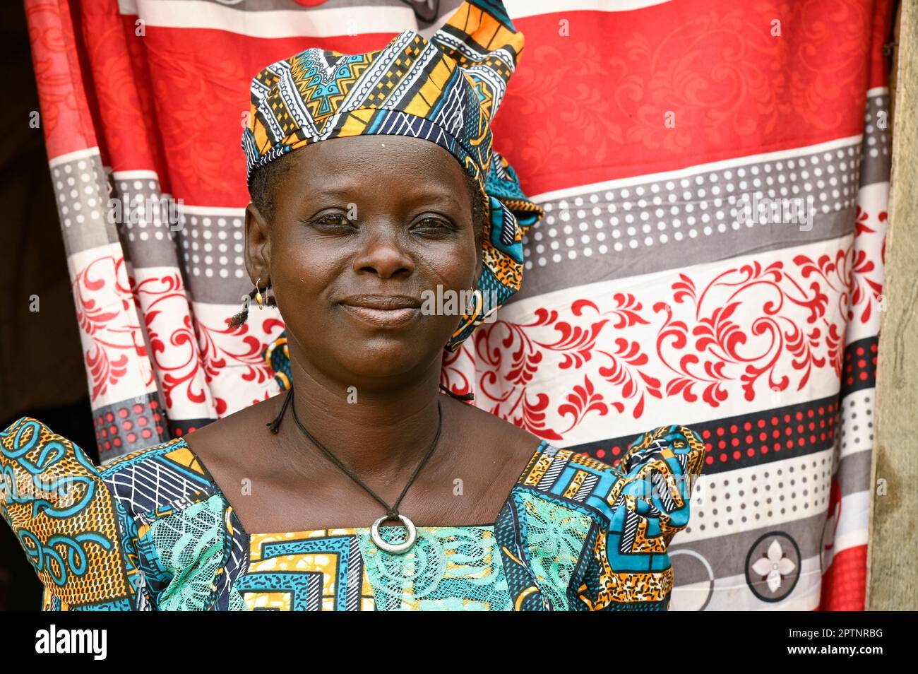 NIGER, Maradi, villaggio Dan Bako, donna in cera colorata abito stampato bambino di tenda colorata / Frau in einem farbigen Batik Kleid Foto Stock