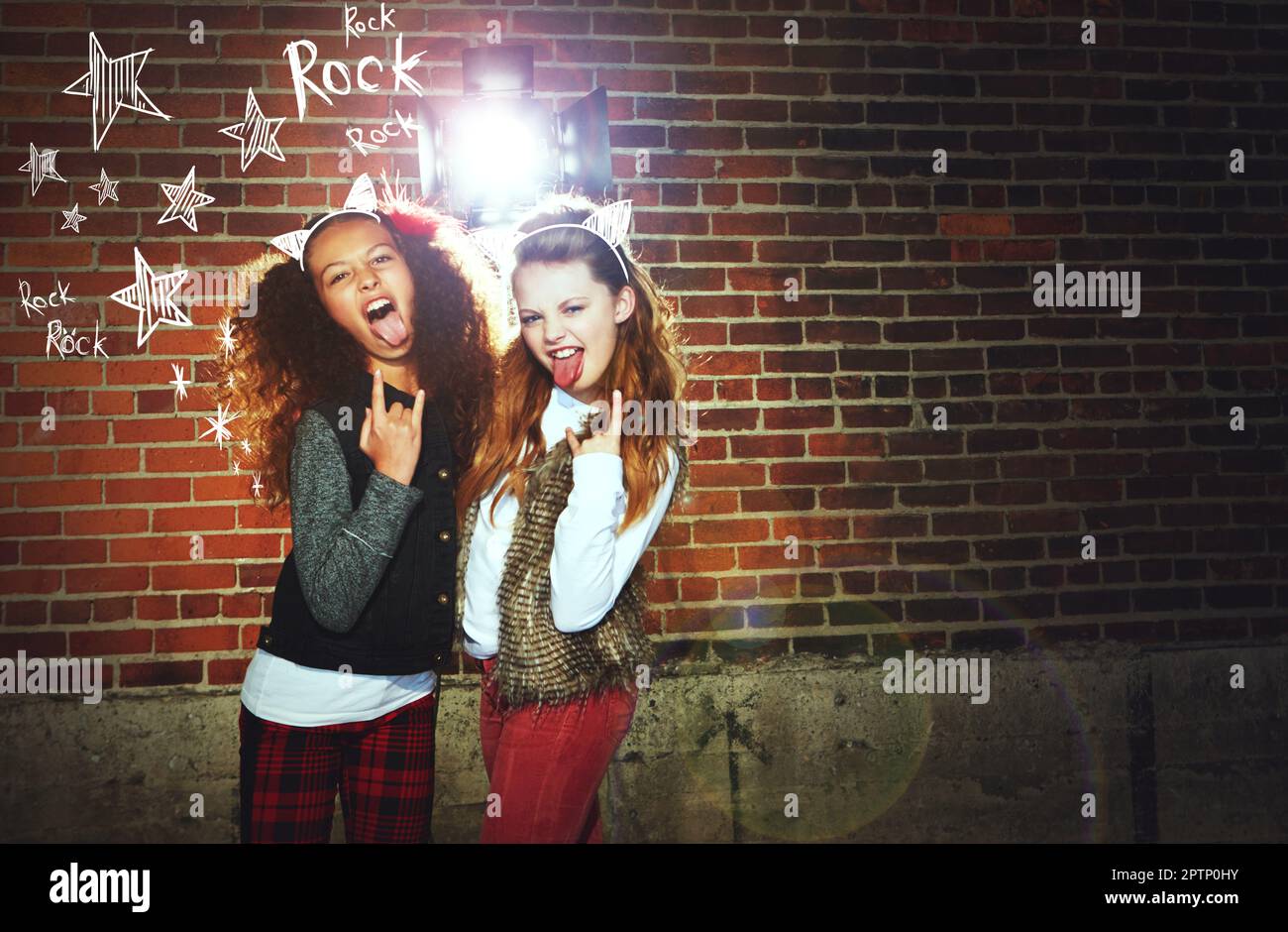 Lunga vita Rock n Roll. due ragazze che tirano i volti e fanno un gesto rock. Foto Stock